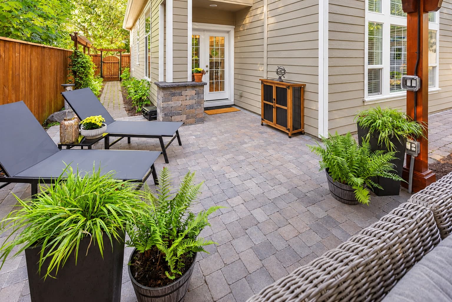 Paver patio with lounge chairs, masonry columns, and landscaped borders