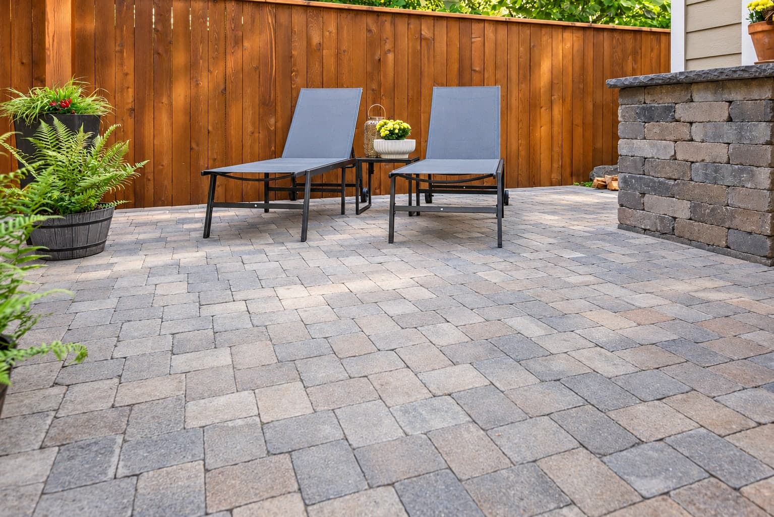 Paver patio seating area beside a timber pavilion and masonry wall